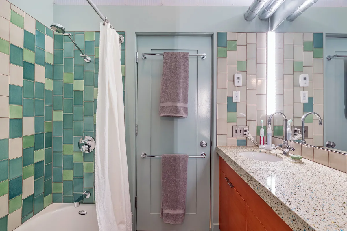 A modern bathroom with a colorful tile wall, sleek countertop, and soft towels. The inviting atmosphere suggests a space for rejuvenation, offering both functionality and comfort for guests.
