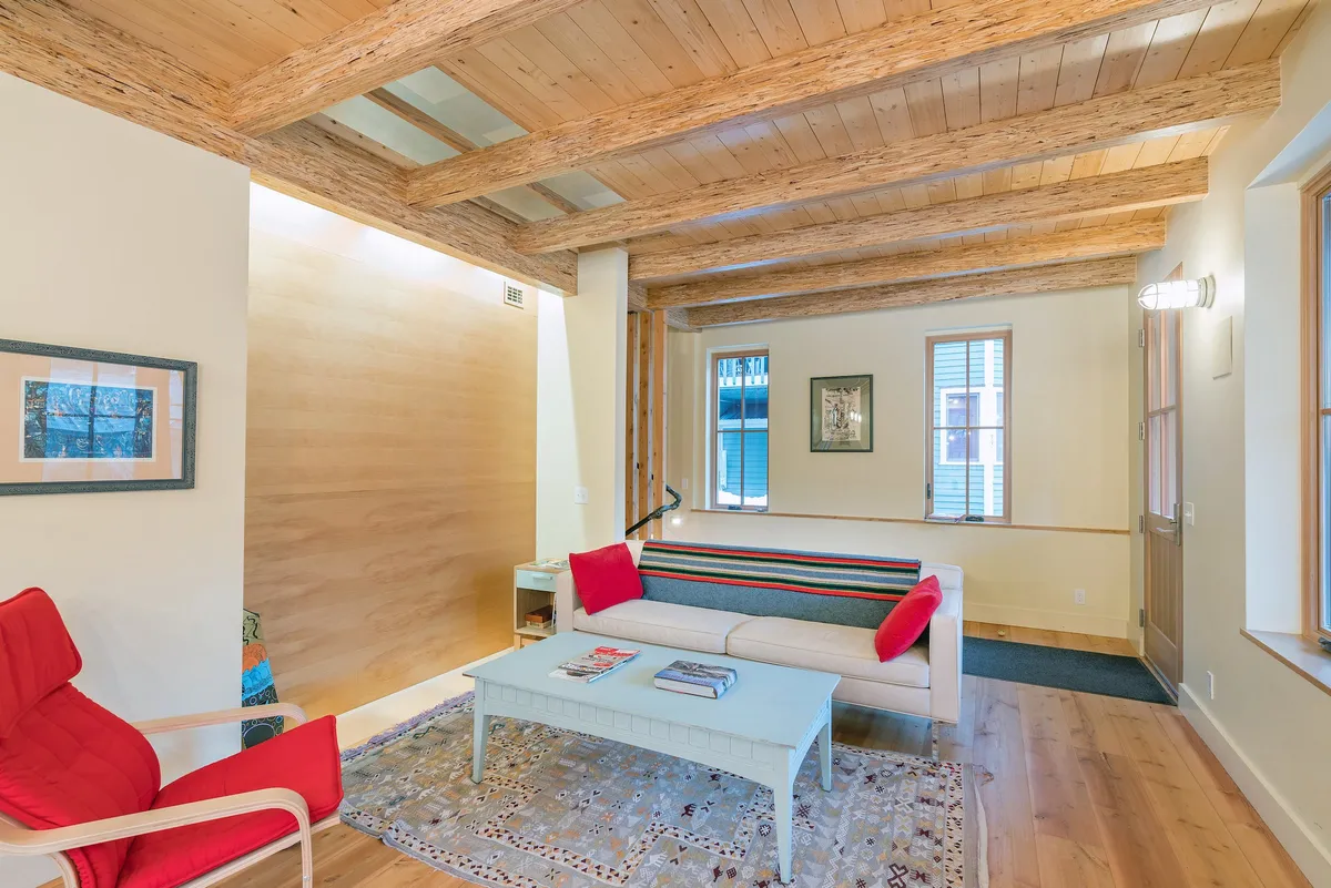 A warm, welcoming sitting area with a red chair, striped sofa, coffee table, and artwork on the walls. This interior feels relaxed and comfortable, inviting conversation, socializing, or a quiet afternoon with a book.